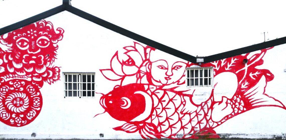 Painted mural of red koi fish on white house.