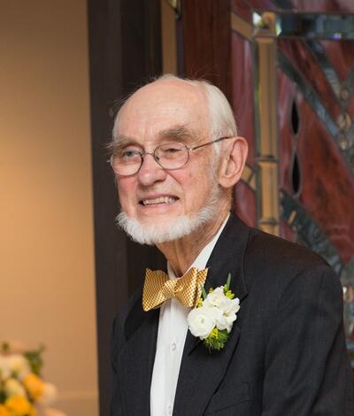 Portrait of Richard Herr, smiling in a black suit.